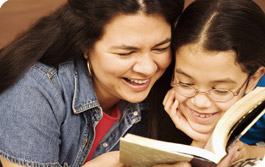 Une femme et un enfant lisant un livre en souriant