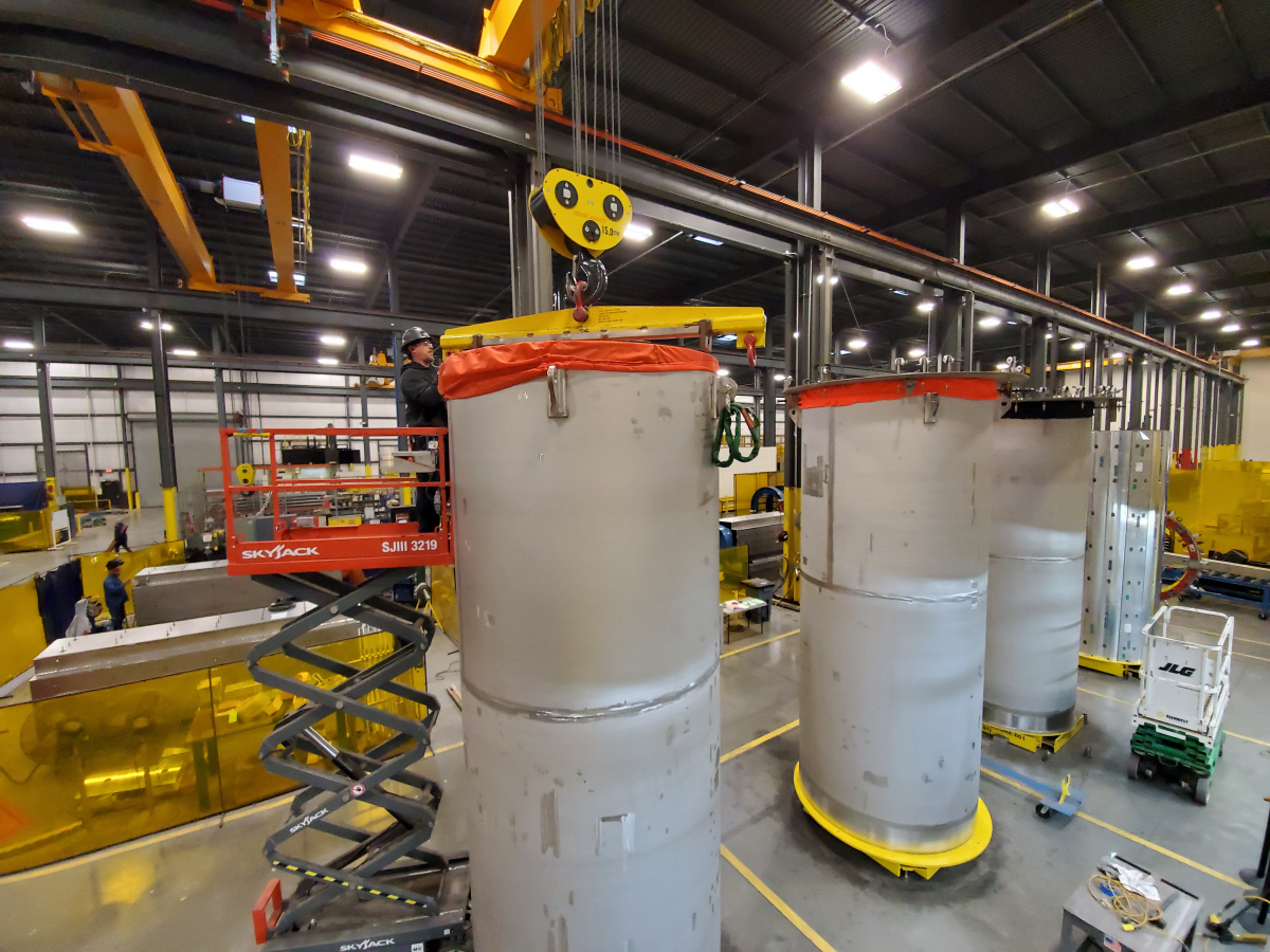 An employee adjusts the overhead crane’s lifting yoke for moving a NUHOMS EOS canister within the TNF Kernersville facility.